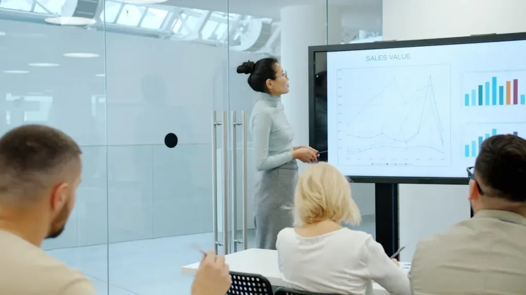 Tendencias inteligencia artificial 2024: transformación empresarial 1 Woman presents charts on a screen to colleagues.